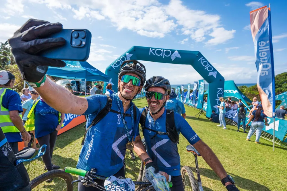 Two Codeo riders in team kit taking a selfie at a mountain bike race finish line