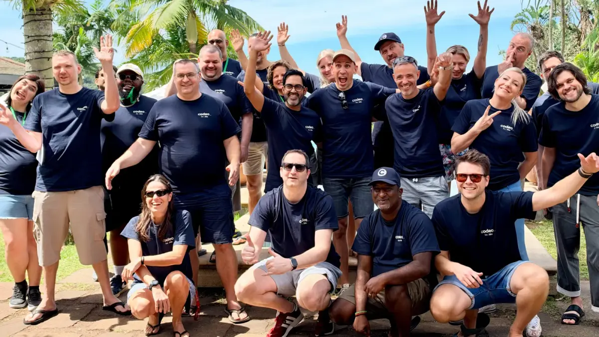 The Codeo team in matching codeo T-shirts, waving and cheering outdoors